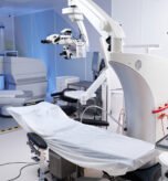 Empty operating room featuring advanced surgical microscope and covered operating table, showcasing modern medical equipment and technology prepared for surgical procedure