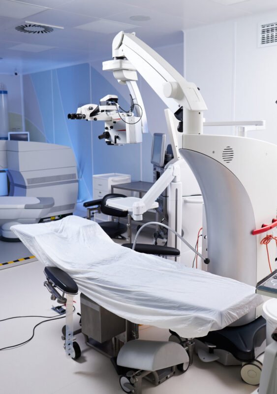 Empty operating room featuring advanced surgical microscope and covered operating table, showcasing modern medical equipment and technology prepared for surgical procedure
