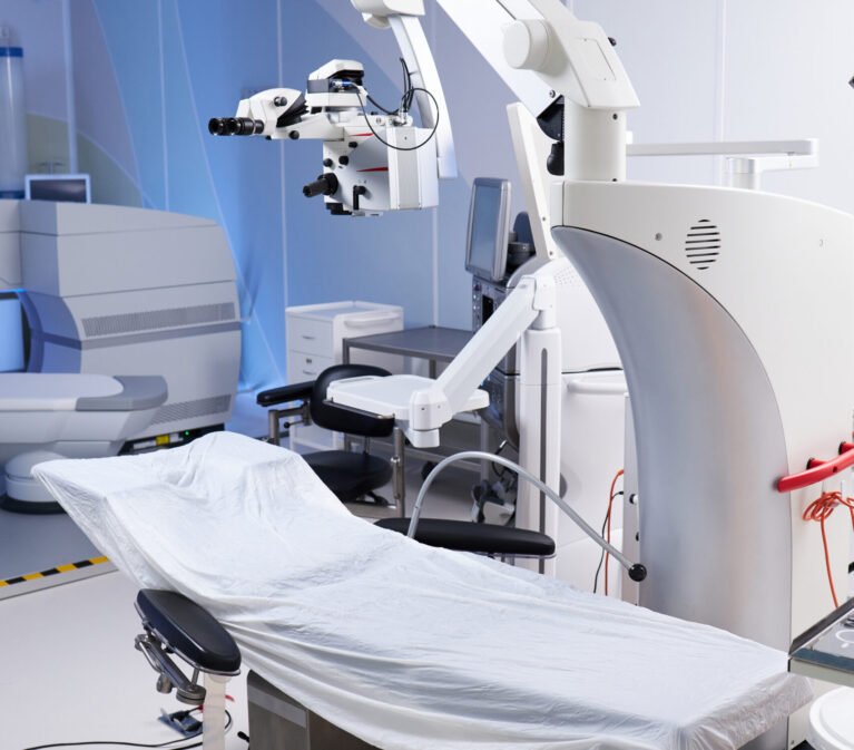 Empty operating room featuring advanced surgical microscope and covered operating table, showcasing modern medical equipment and technology prepared for surgical procedure